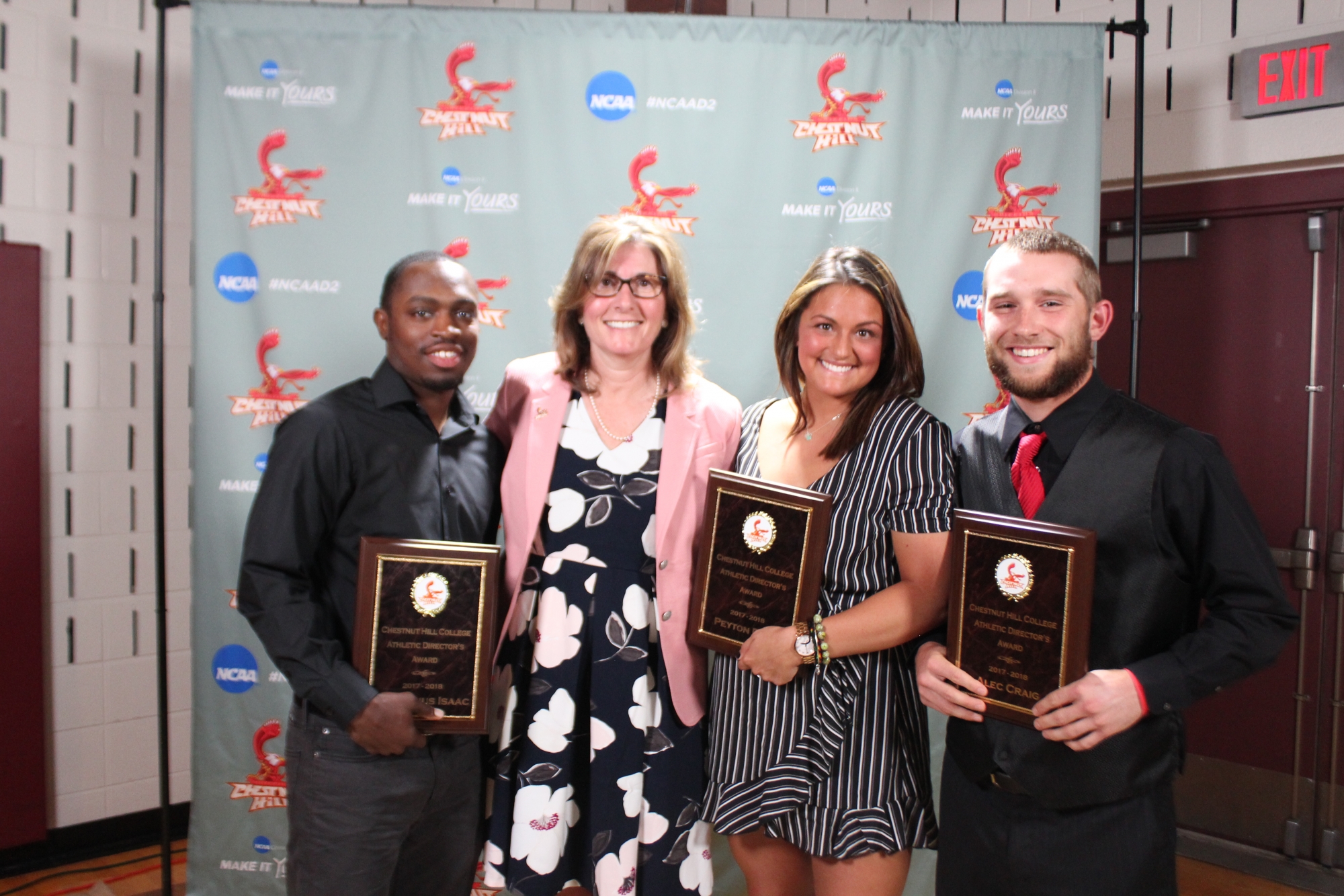 Lynn Tubman stands with (left) Demetrius Isaac, (inner right) Peyton Reno and (right) Alec Craig, winners of this year's Athletic Directors Awards.