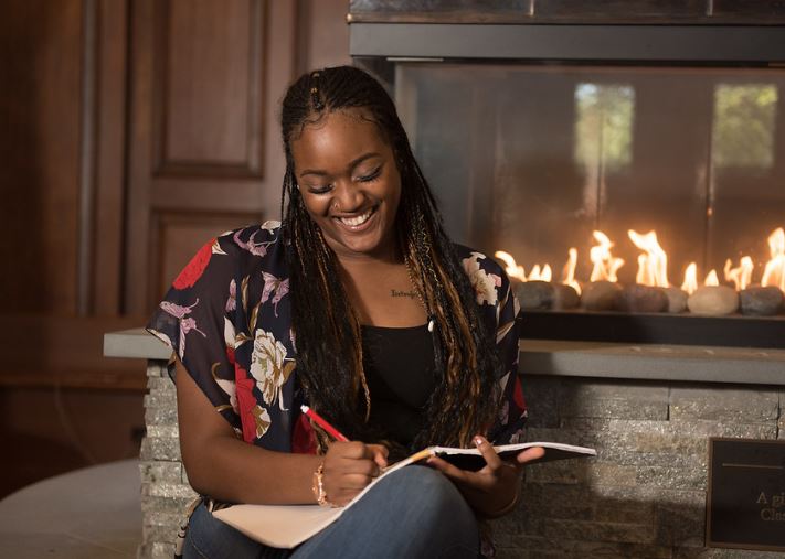 woman smiling with writing next to a fireplace
