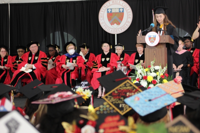 Amidst a sea of decorated caps, Gianna Vassulluzzo '22 stands on stage to offer the student welcome during Saturday's ceremony.