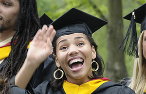 Woman in cap and gown smiling and waving