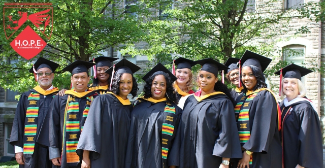adult students in graduation gear standing outside; H.O.P.E. red logo on the upper right side