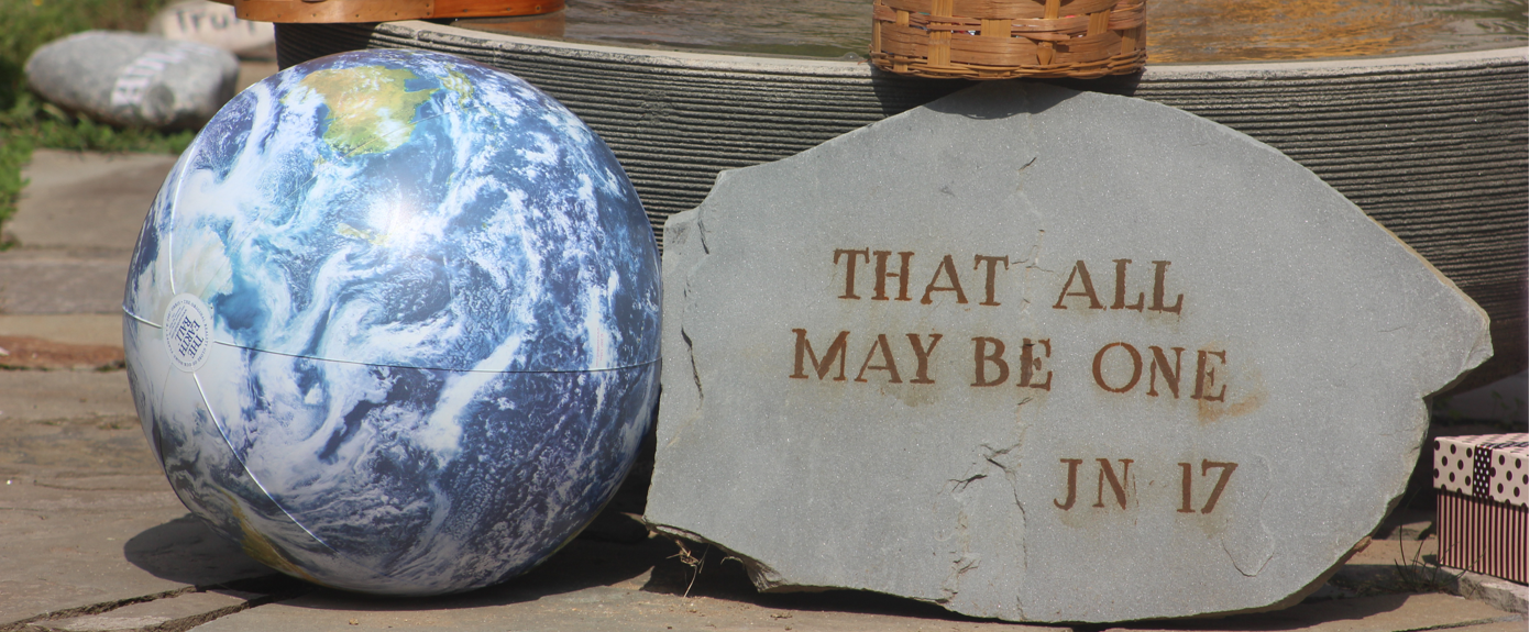 globe with stone that reads "that all may be one"