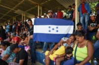 Honduran migrants sitting next to Honduran flag