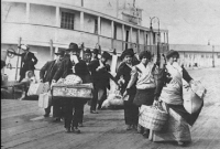 B&W photo of immigrants getting off boat at Ellis island