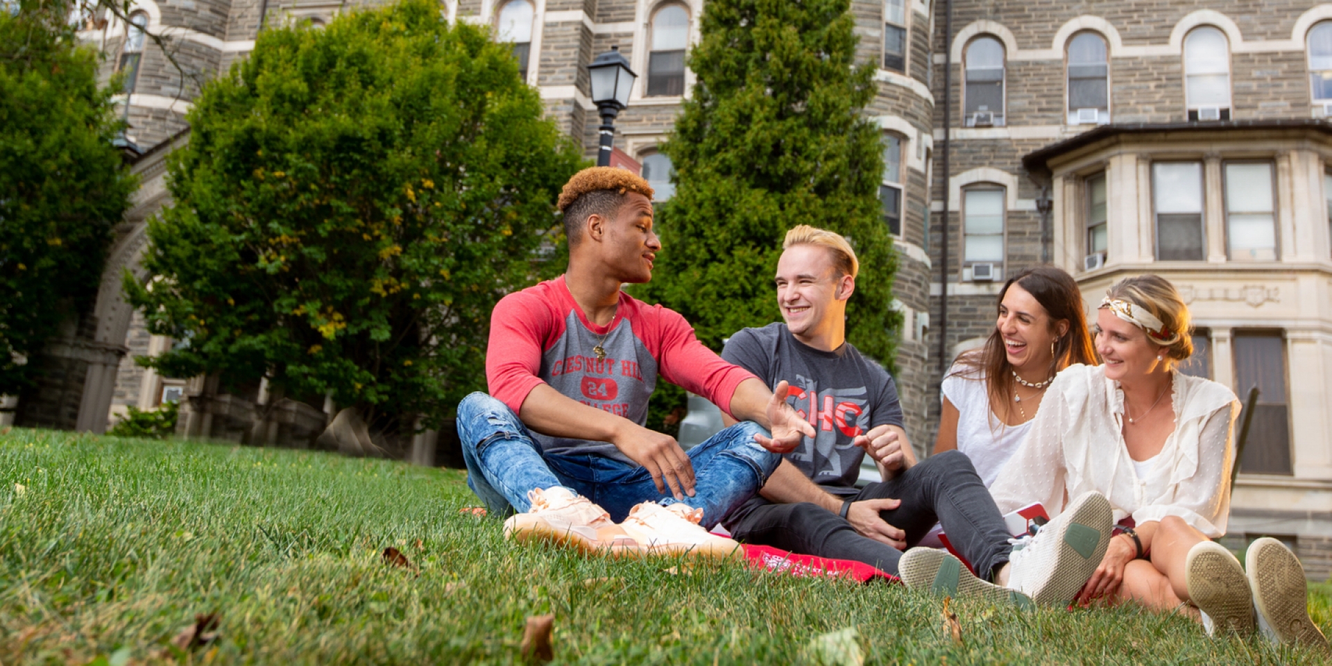 students sitting on the lawn at chestnut hill college