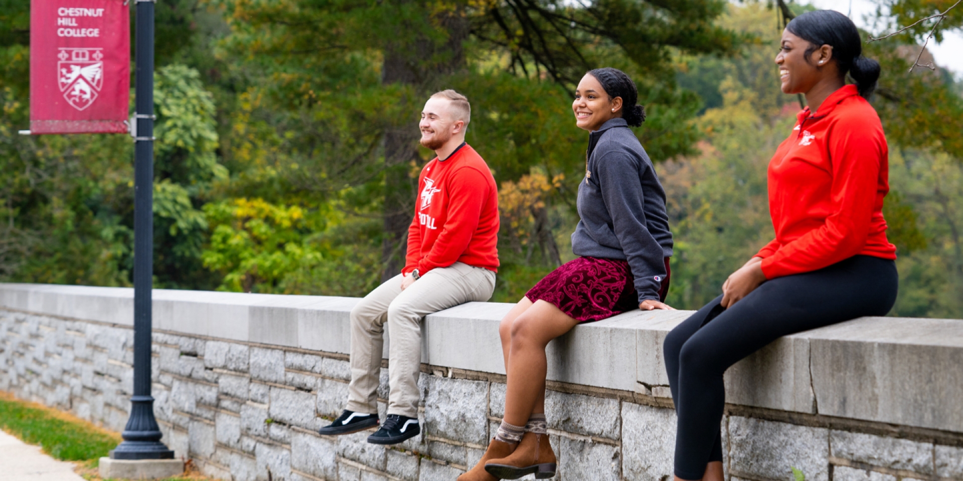students sitting on a wall at chestnut hill college