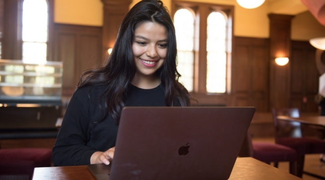 Student smiling as she works at computer