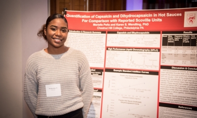 student standing with senior seminar poster