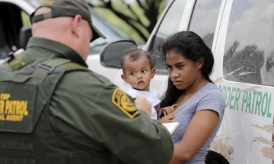 Migrant woman holding baby glaring at border control