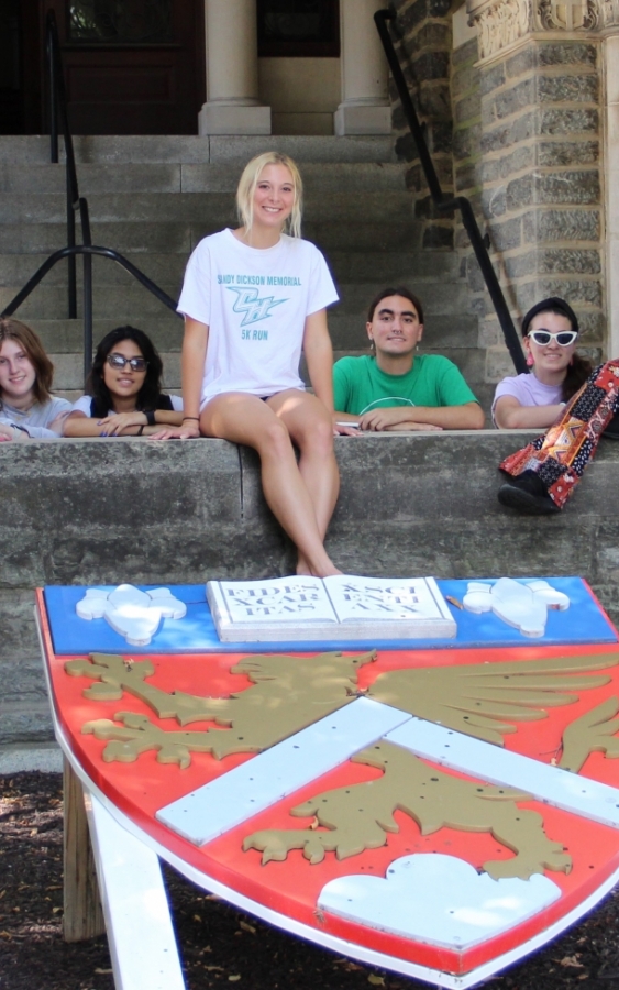 students sitting on a ledge outside of Chestnut Hill College