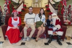 Couple sits with Santa and Mrs. Claus in Christmas scene