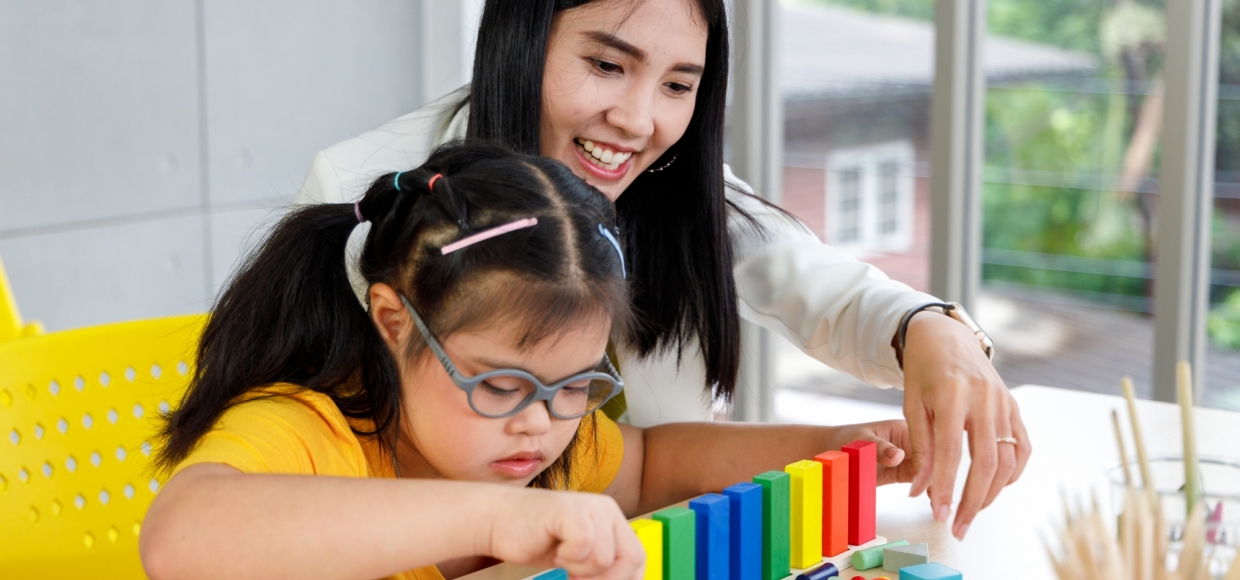 Adult helping child arrange colored blocks