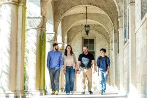 Four people walk under an archway