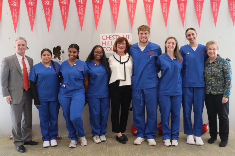 group of nursing students and administrators standing in front of white wall