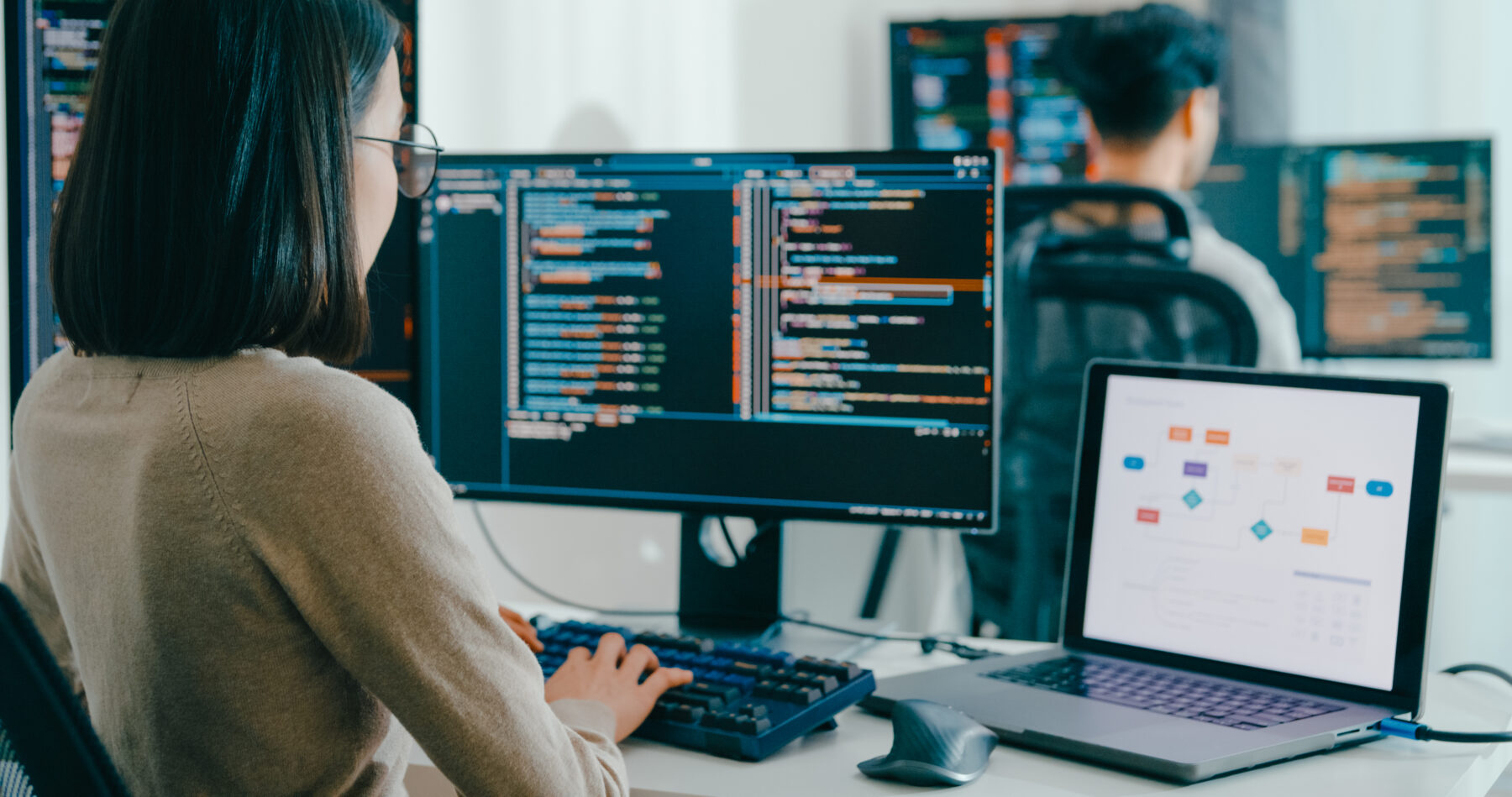 woman working on data programs across multiple monitors