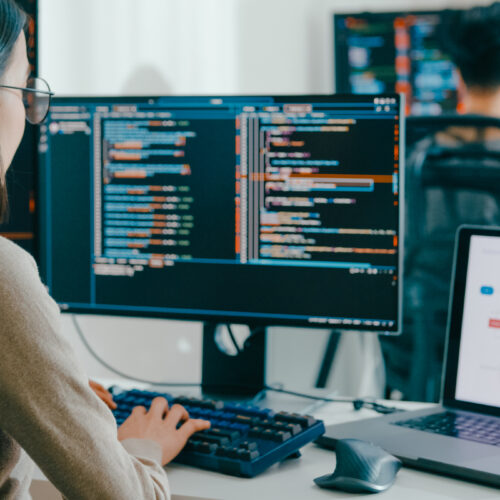 woman working on data programs across multiple monitors