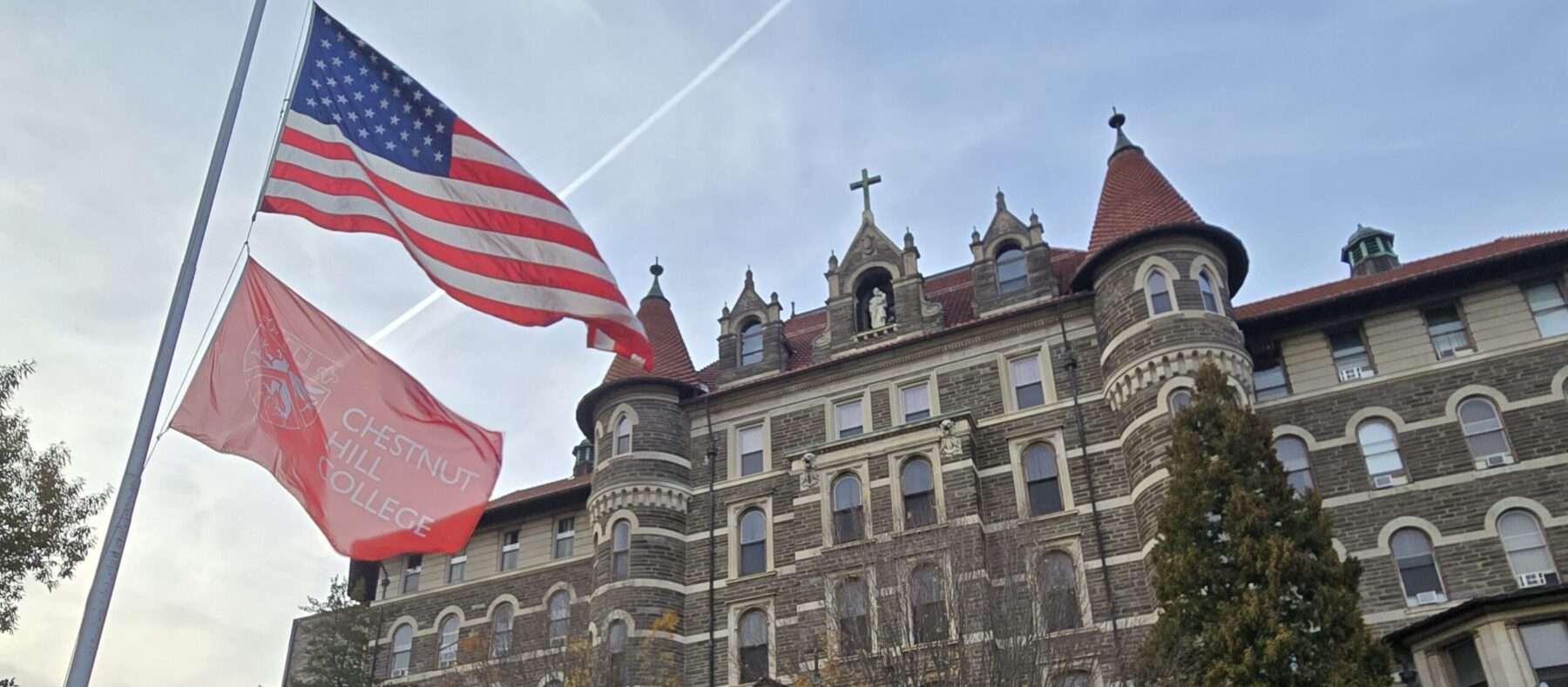 American flag and college flag in front of college campus building