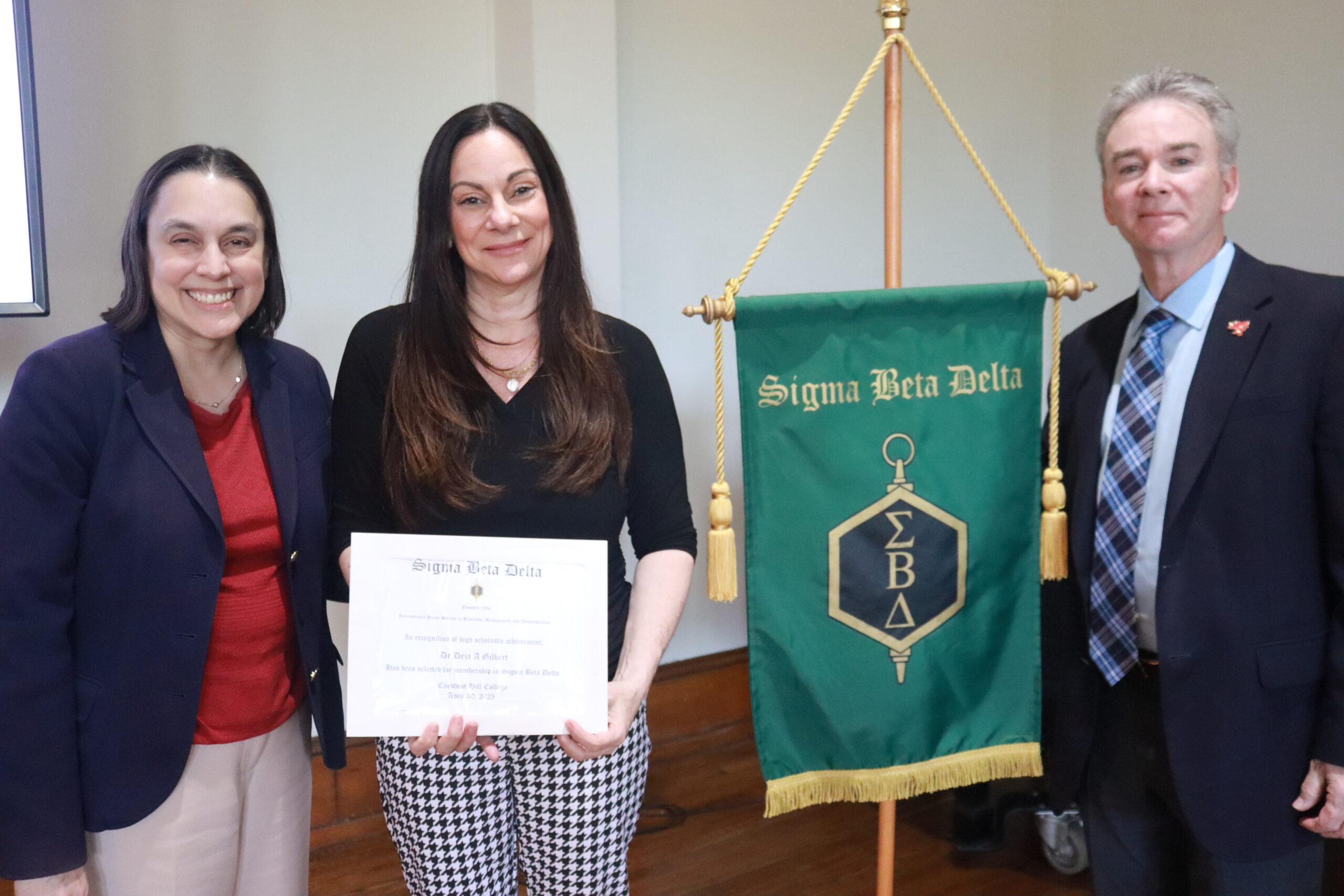 three individuals smiling as a woman receives an award