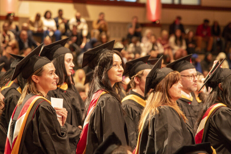 group of students standing in line preparing to graduate with master's degrees