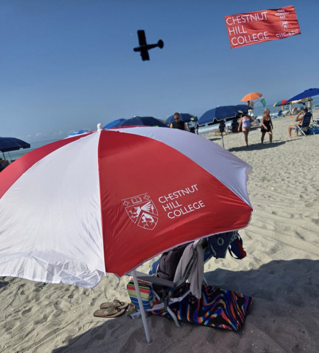 Chestnut Hill College umbrella and banner plane on a beach
